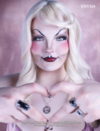 a woman with makeup on her face making a heart sign