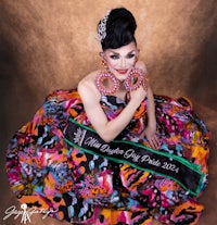 a woman in a colorful dress posing with a sash